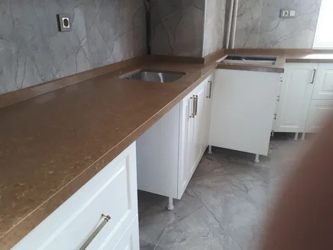 Kahverengi tezgah ve beyaz mutfak dolapları